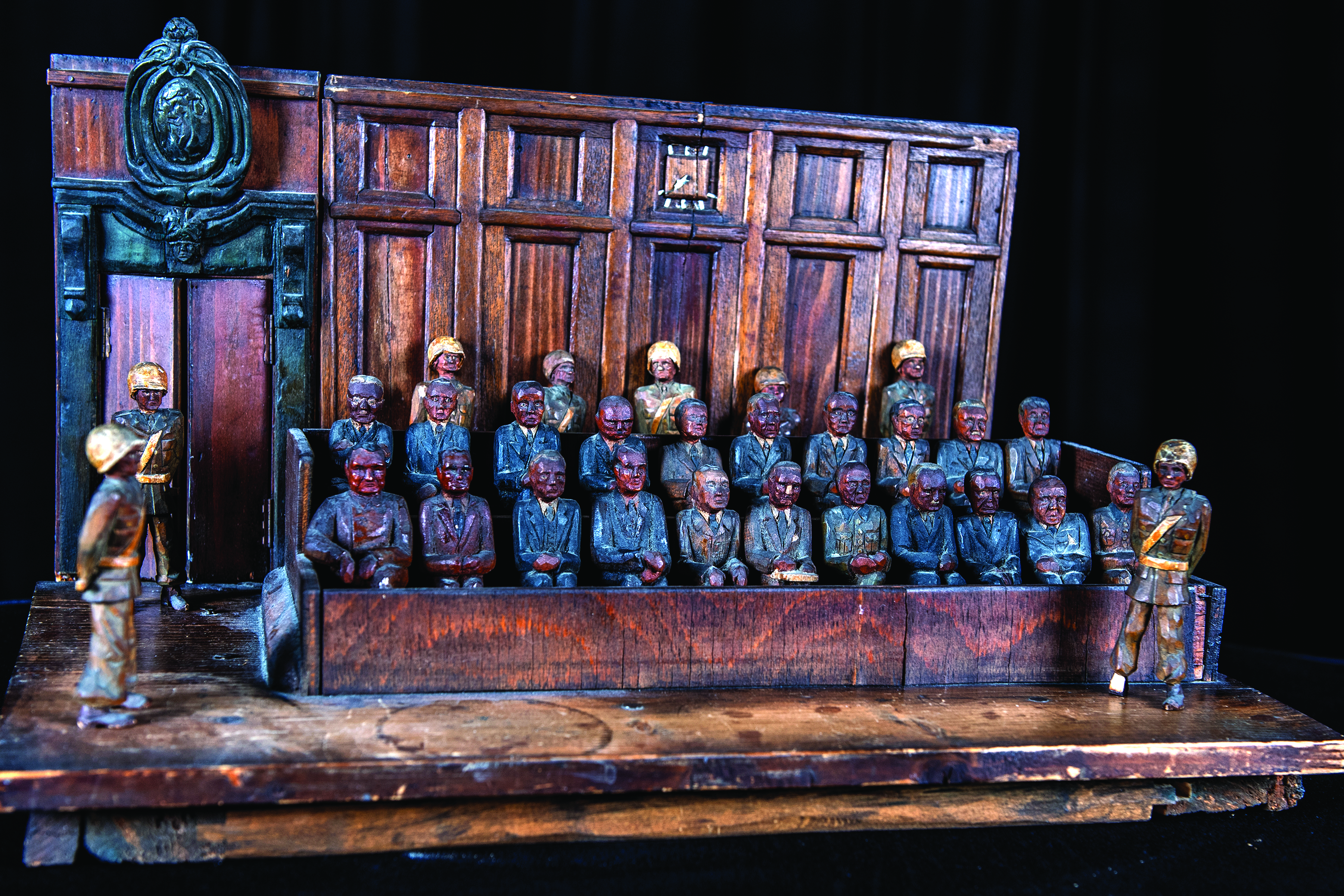A hand-carved sculpture of the IMT defendants’
        box, made by one of the American guards. The
        sculpture is on display in the library at TJAGLCS.
        (Credit: Jason Wilkerson, TJAGLCS)